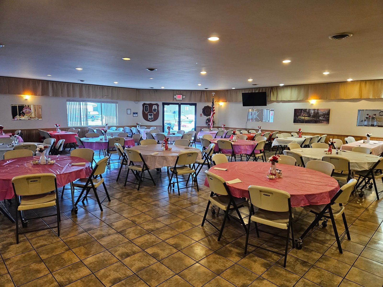 Banquet hall set with round tables and pink tablecloths for an event