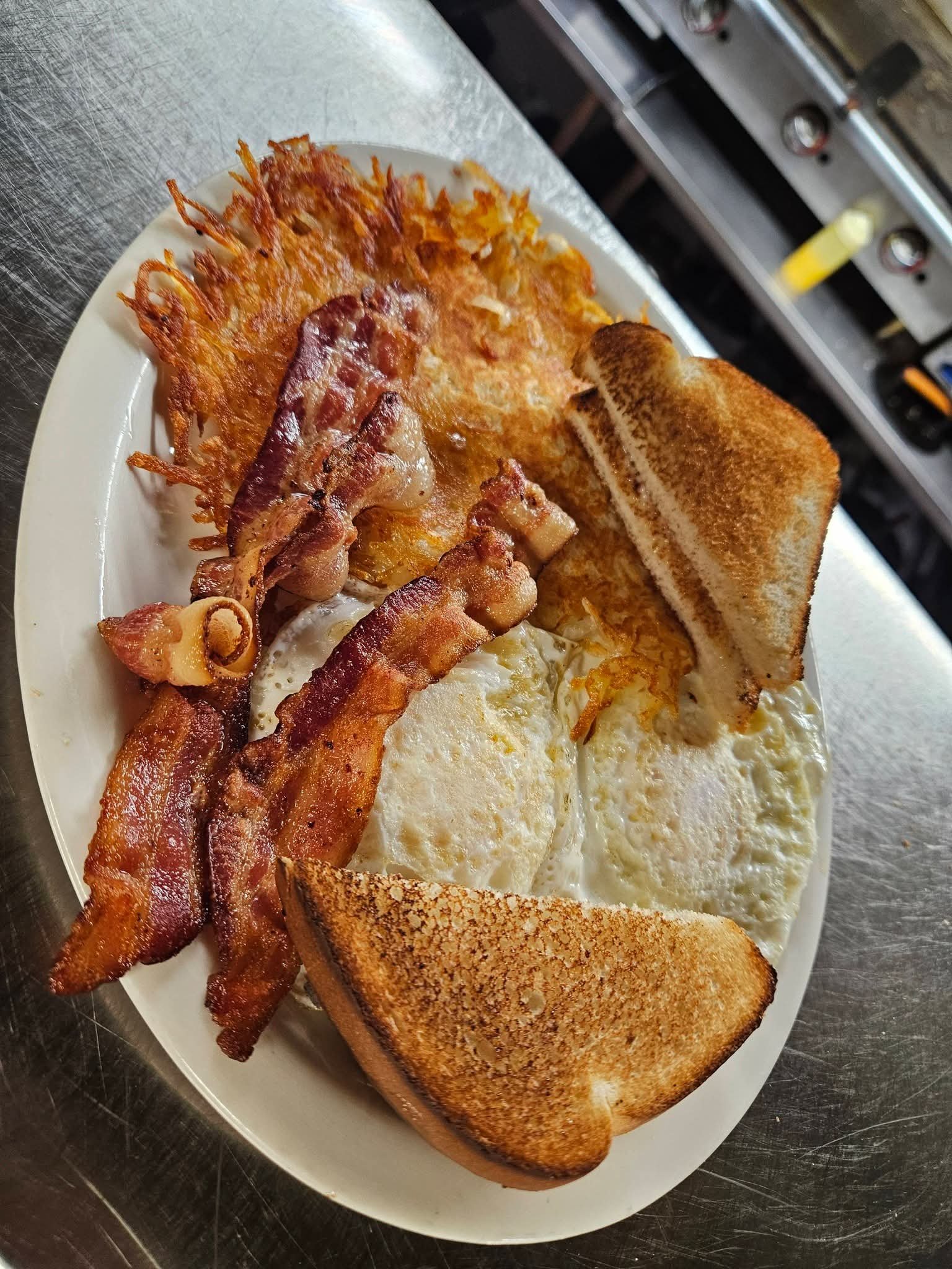 Breakfast plate with bacon, eggs, hash browns, and toast